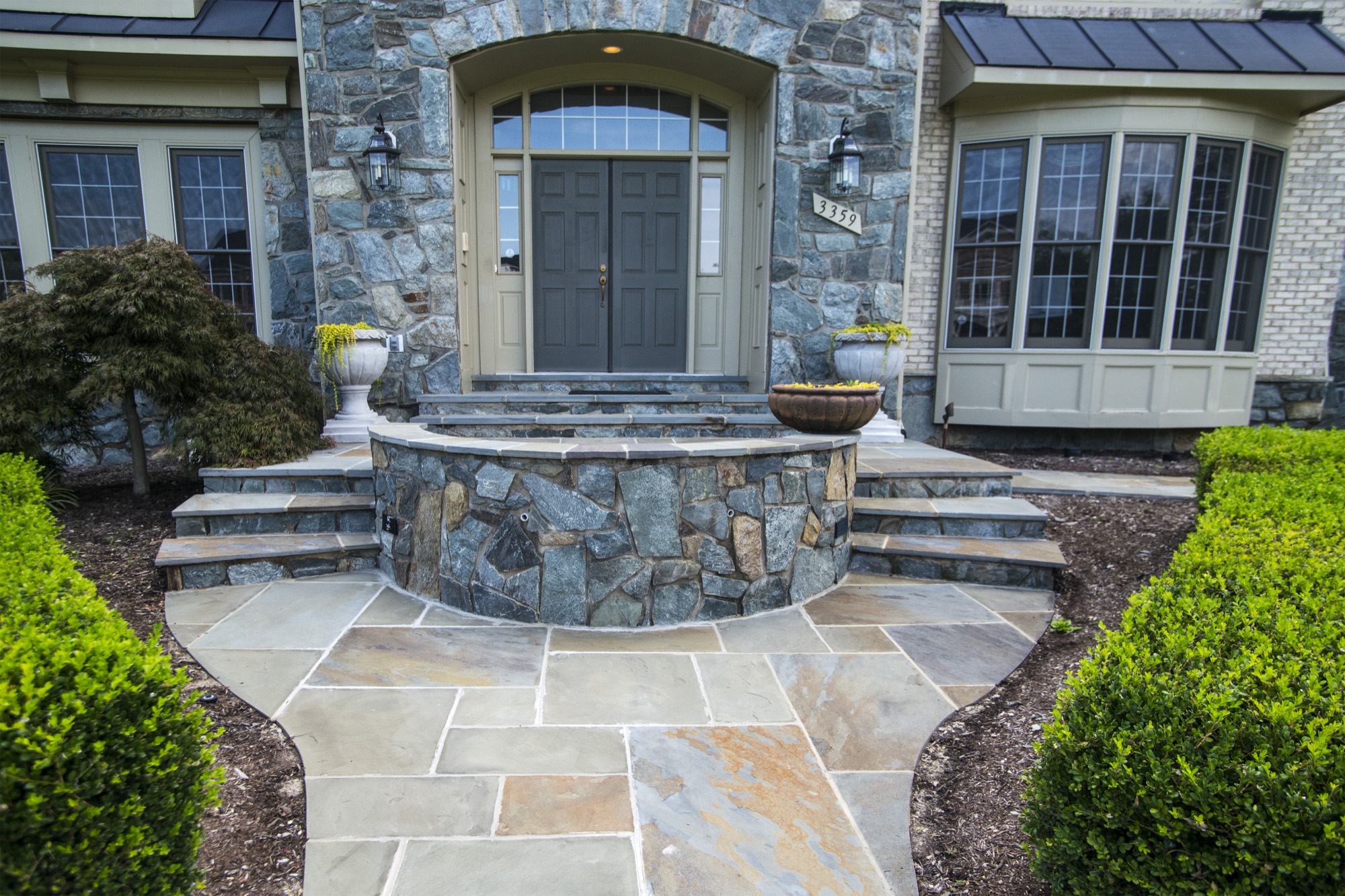 Natural stone front entrance with flagstone landing, curved sitting wall, and steps in Northern Virginia