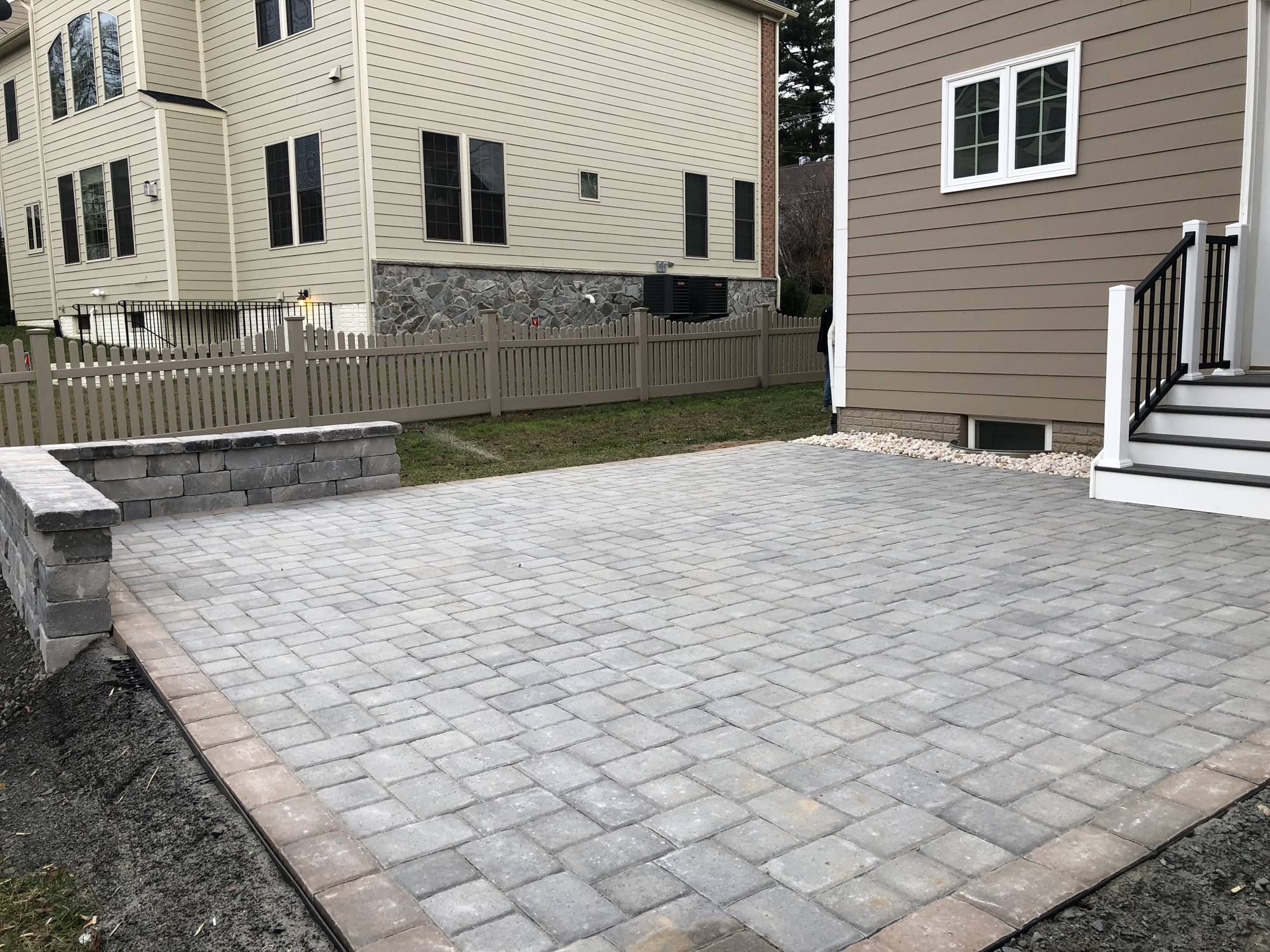 Light paver patio with sitting wall behind a Northern Virginia townhome