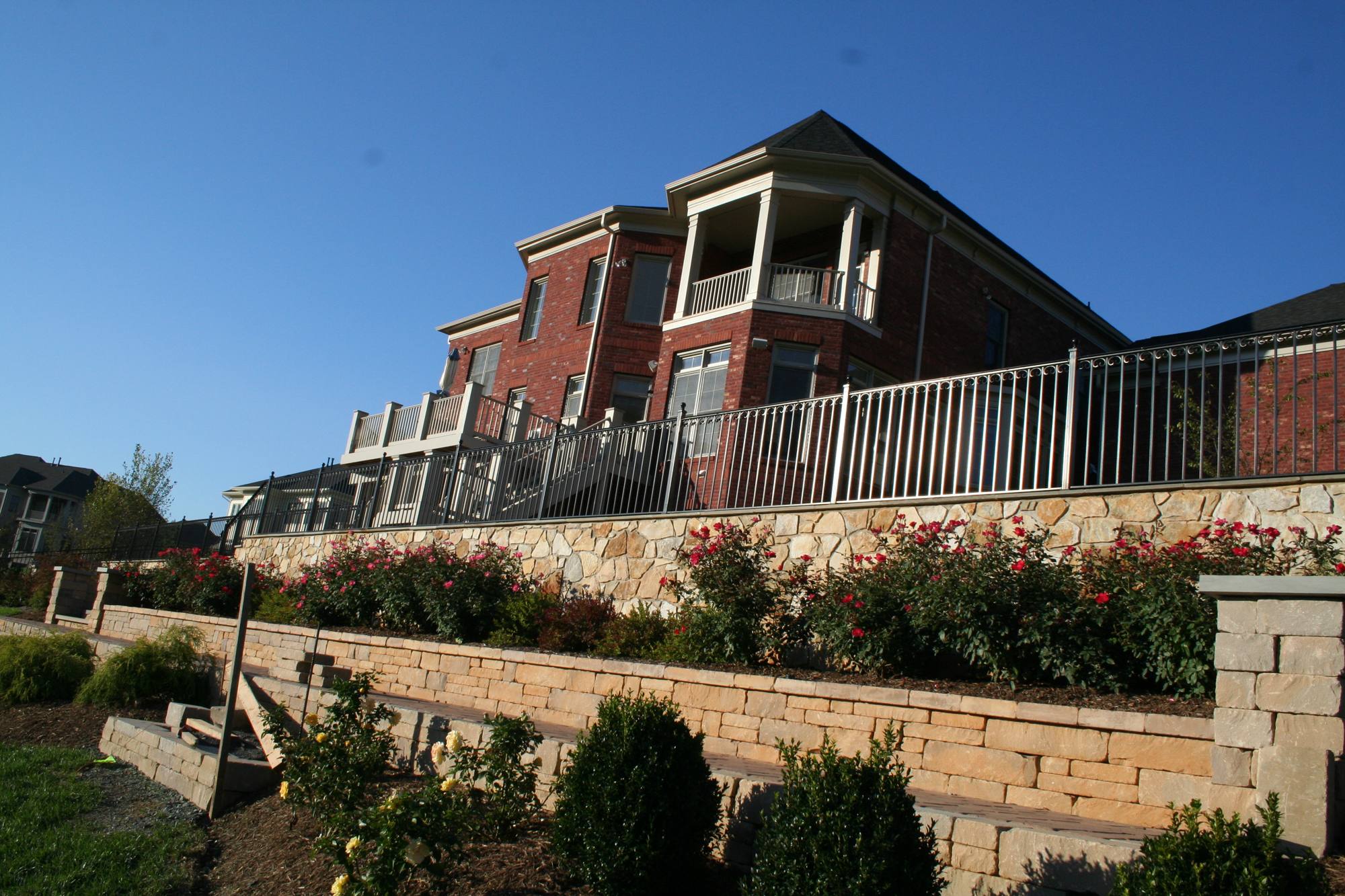 Natural stone veneer retaining wall with rose garden and iron railing in Northern Virginia