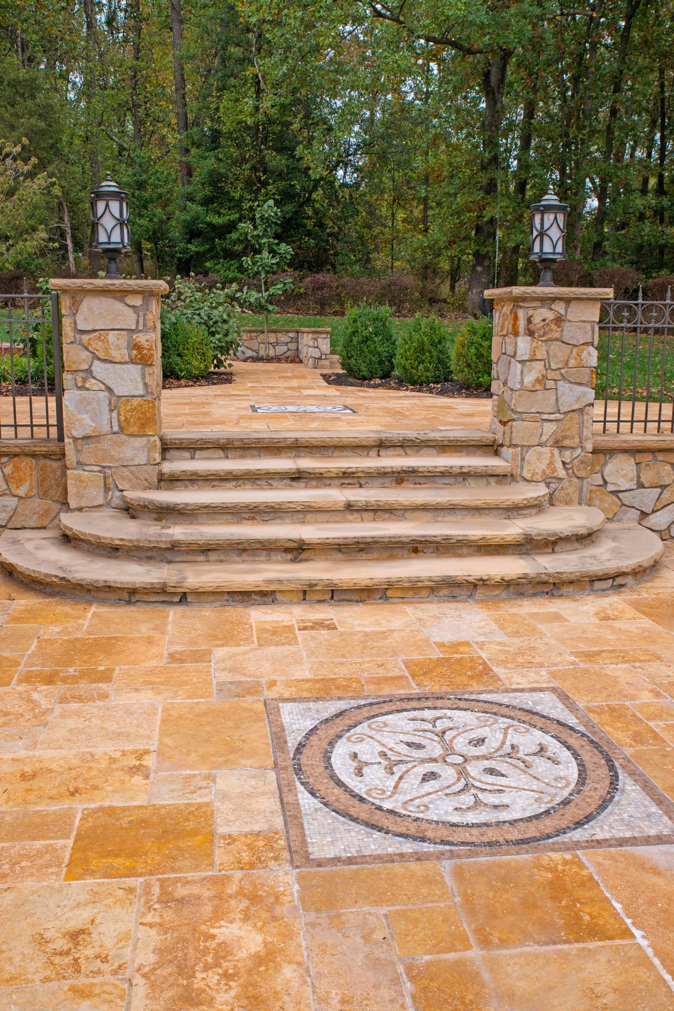 Curved travertine steps leading to a patio with medallion inlay in Northern Virginia